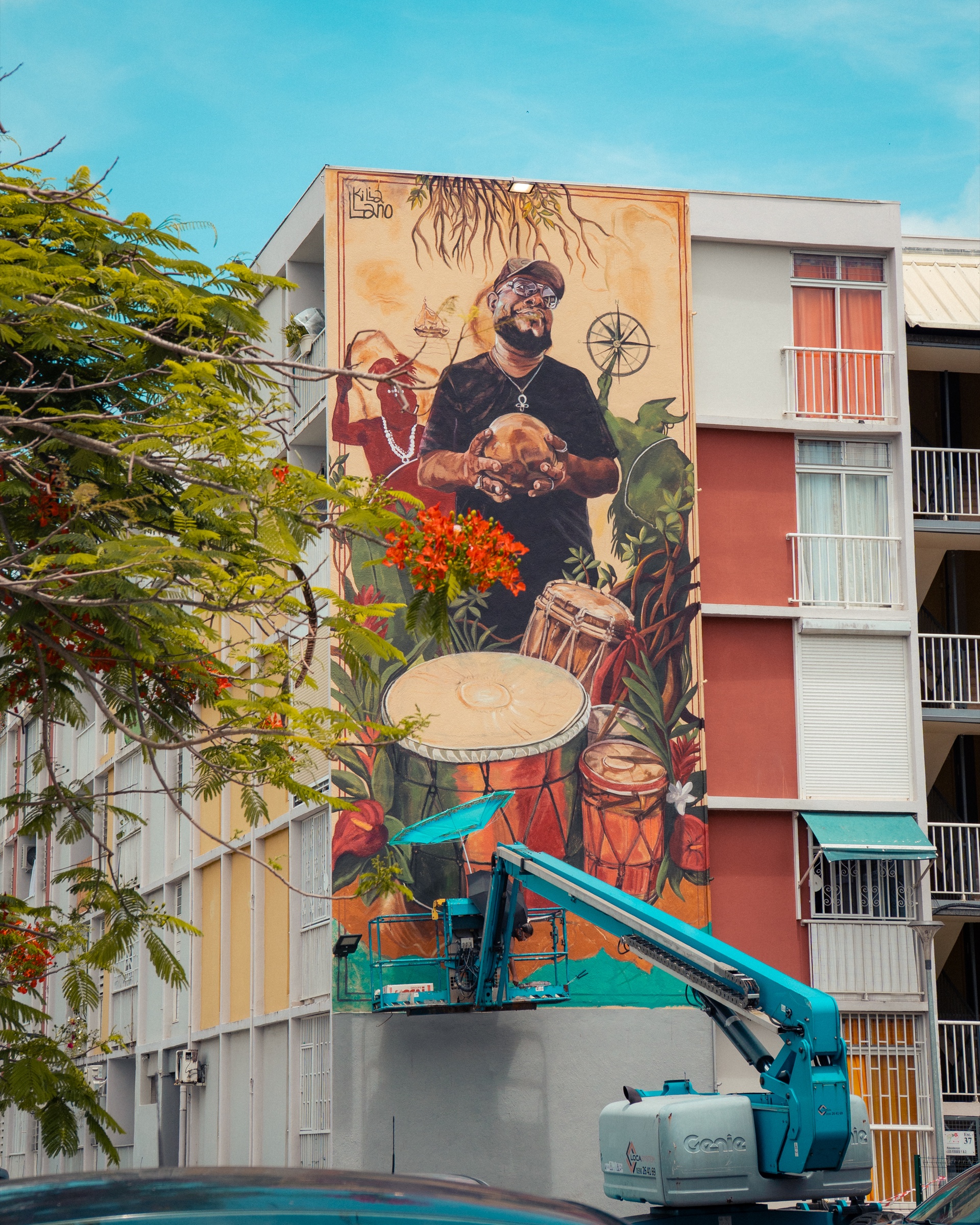Fresque dédiée au tambour photographiée derrière les arbres