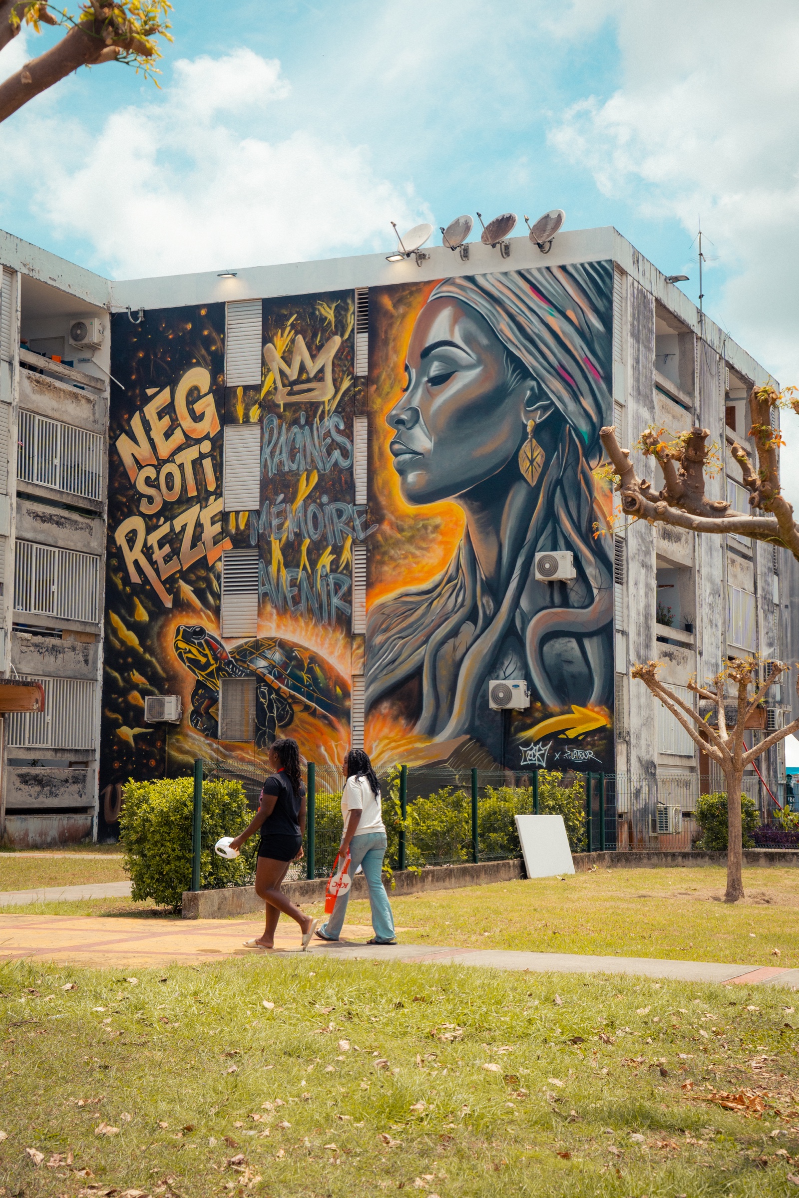 Deux passantes devant une grande fresque urbaine guadeloupéenne