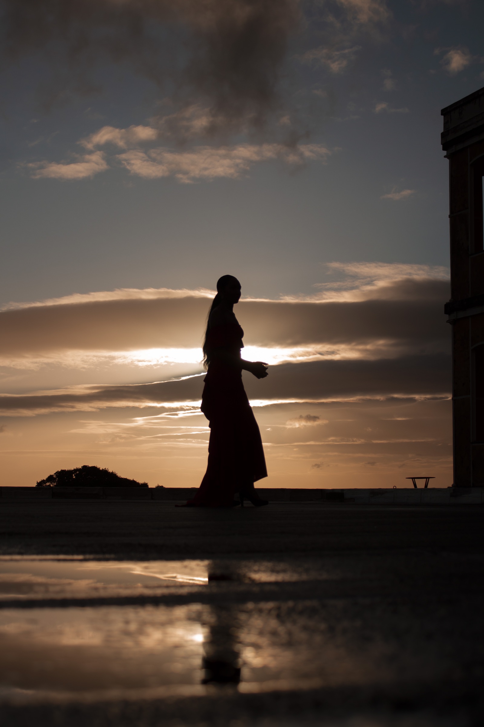 Silhouette marchant devant le soleil couchant et son reflet