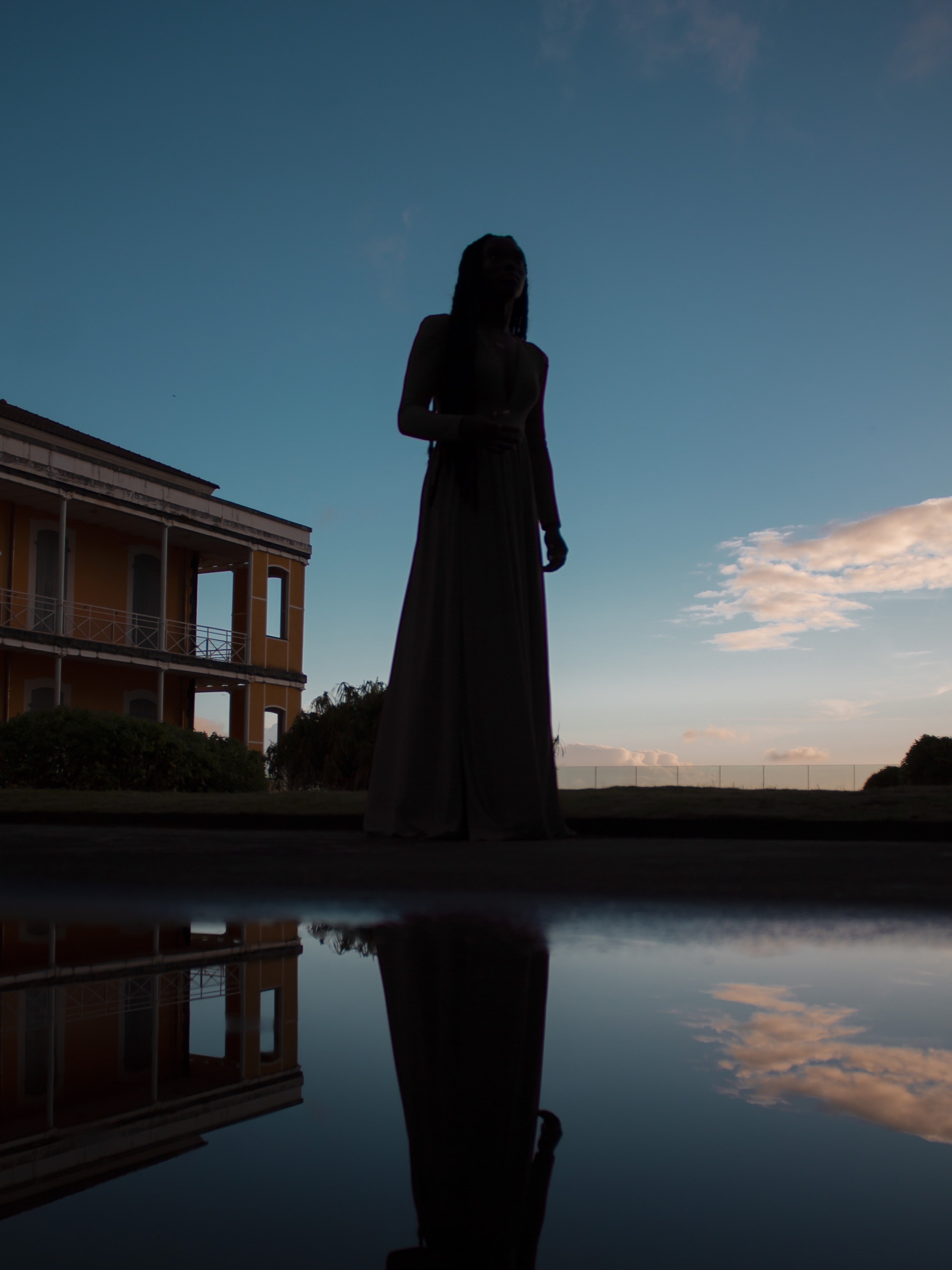 Silhouette en robe longue reflétée dans l’eau au crépuscule